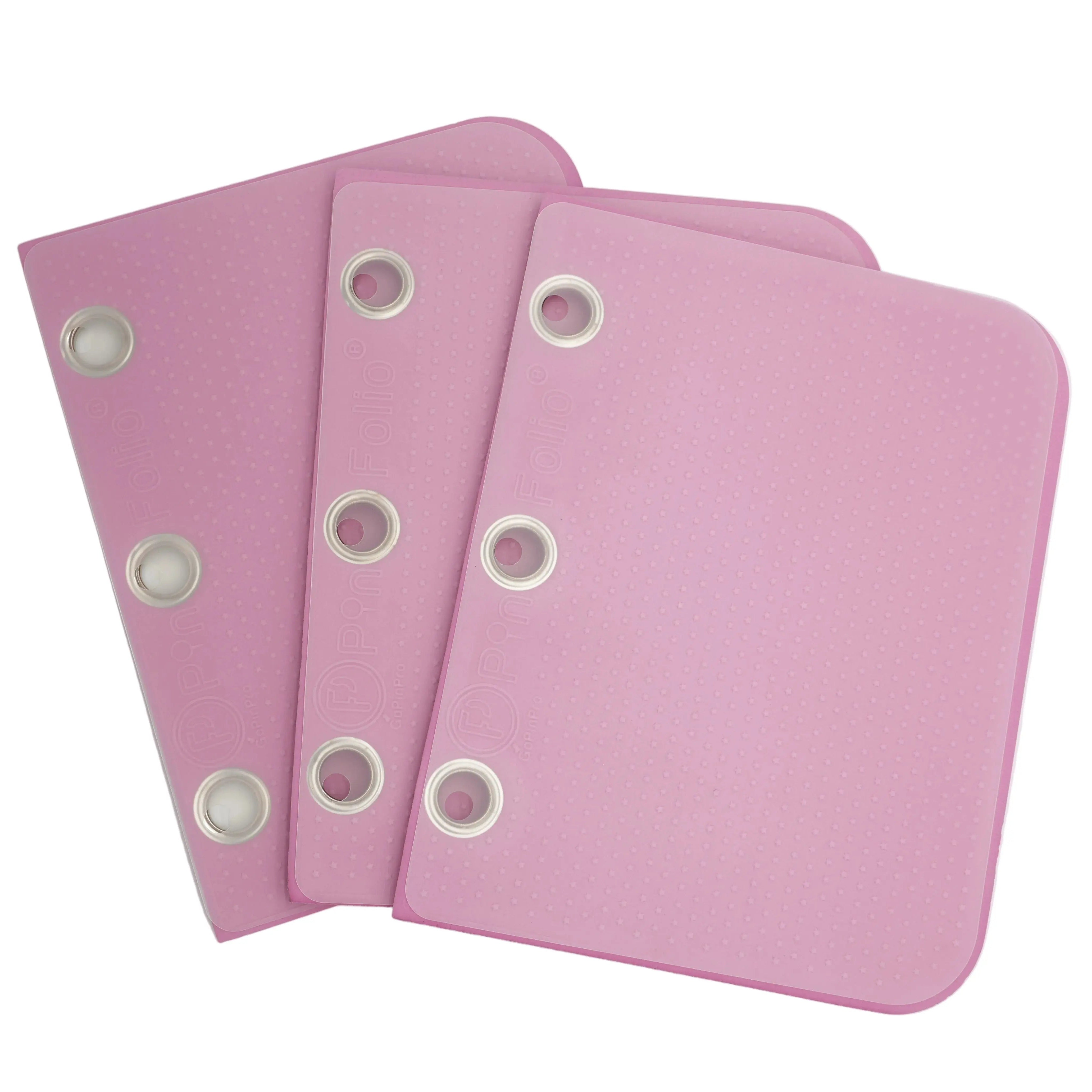 Three pink binder rings with white plastic grommets, arranged in a fan shape on a light gray background.